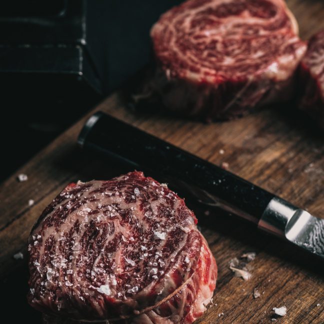 Two slices of raw wagyu steak on a chopping board