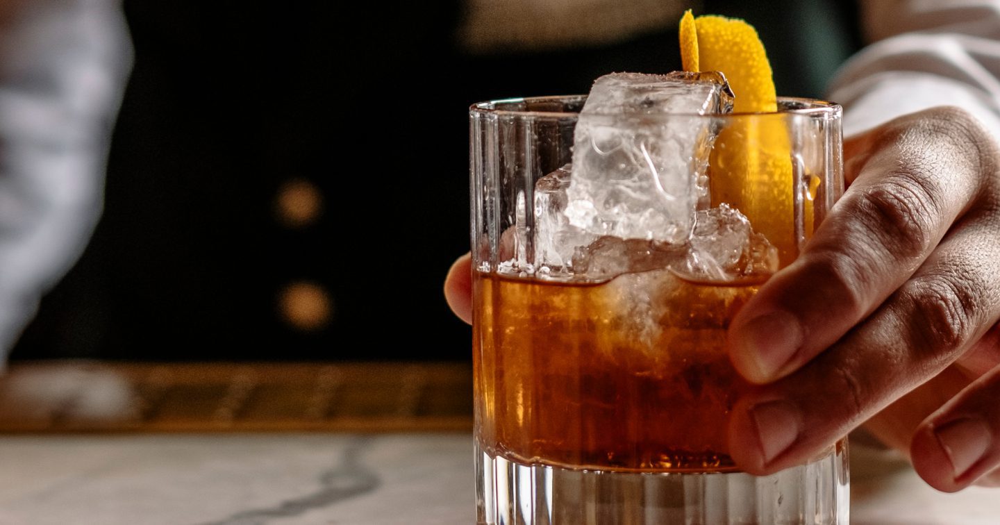 Hand holding old-fashioned cocktail
