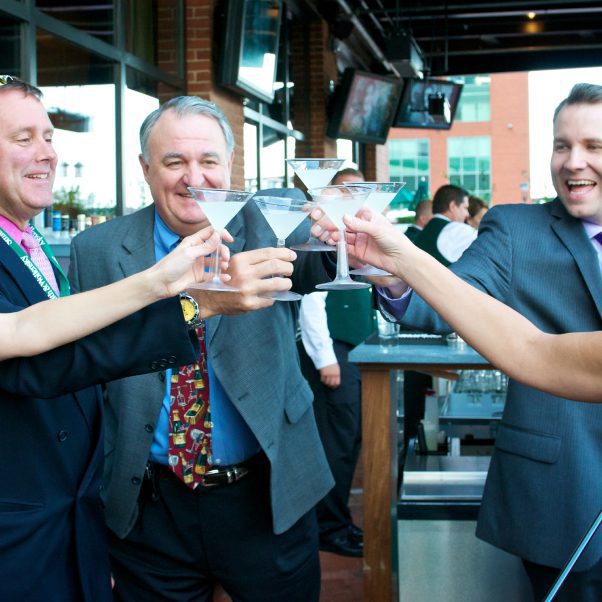 A few gentleman are saying cheers with cocktails