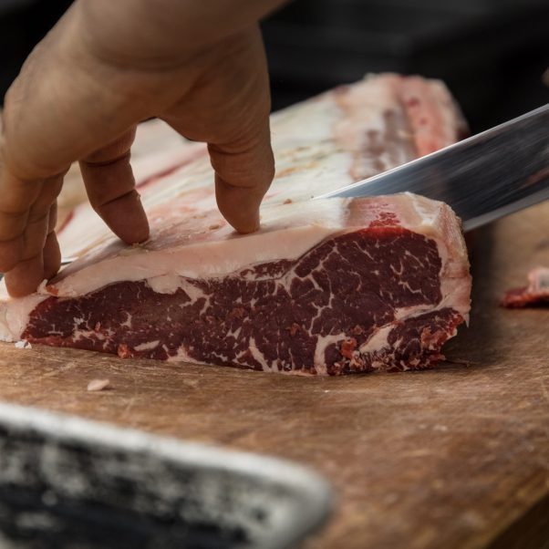 Butcher is slicing steak meat