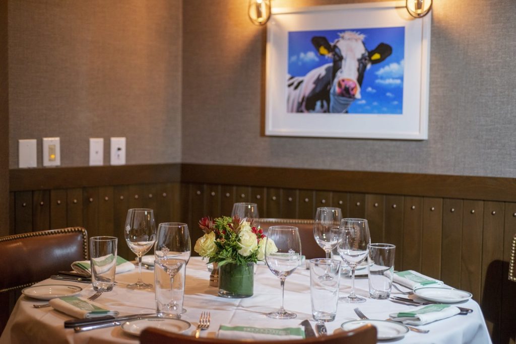 Table setting in the Brandeis Room at S&W Wellesley, with a cow picture on the wall