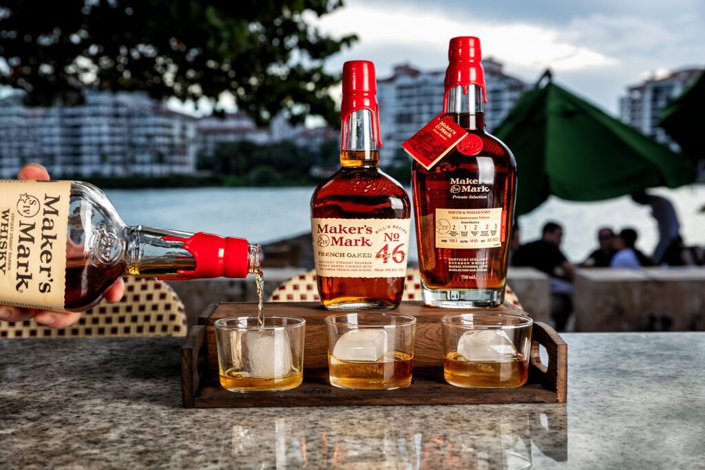 Maker's Mark whisky being poured on rocks into 3 glasses