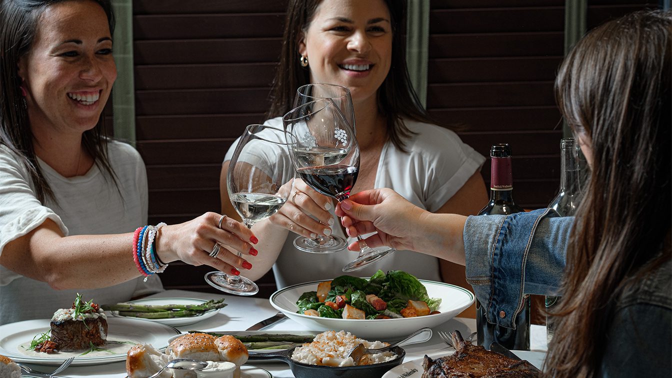 Three women are raising glasses with wine