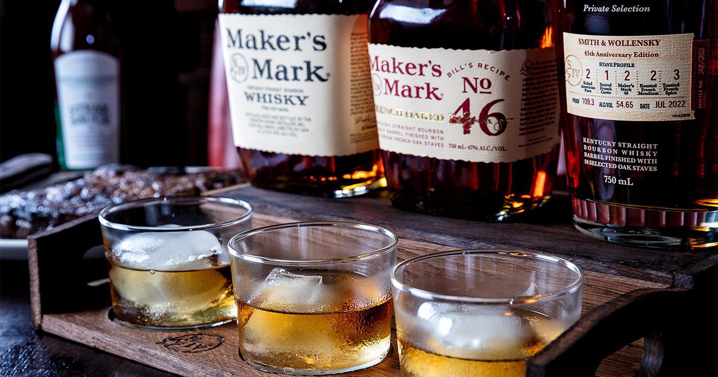 Maker's Mark whisky bottles and three glasses with whisky on rocks