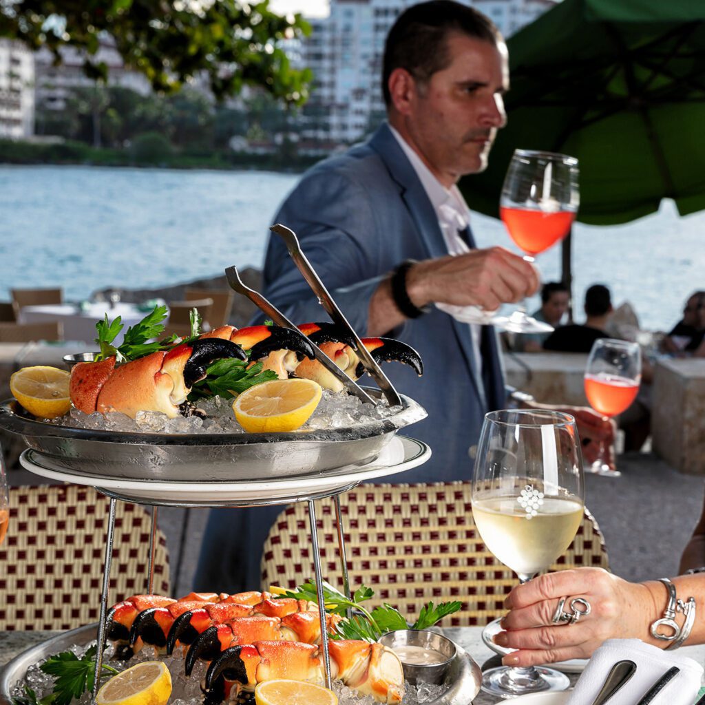 Man is holding a glass of drink in front of an S&W seafood platter