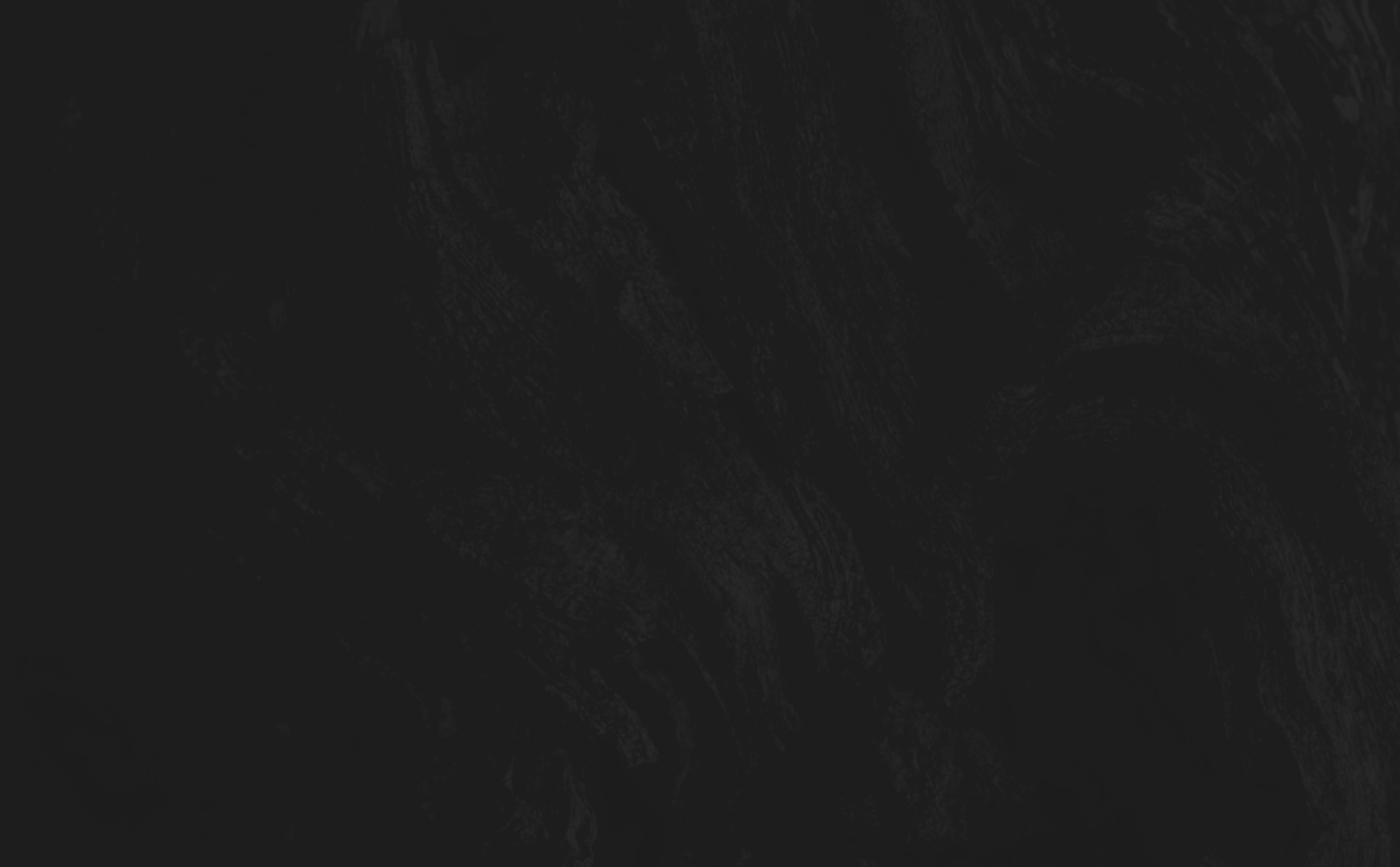A dark, almost black textured surface with faint, swirling woodgrain-like patterns barely visible in the shadows.