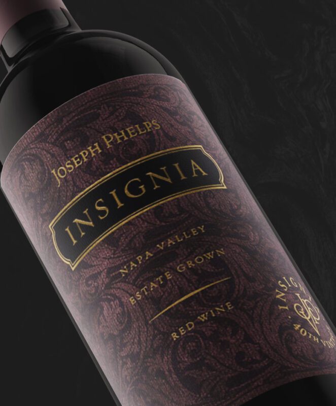 A close-up of a Joseph Phelps Insignia Napa Valley red wine bottle, showing its ornate purple and gold label with intricate patterns and elegant lettering.
