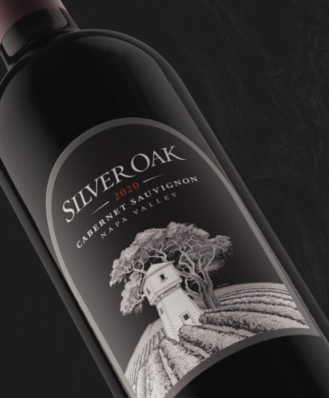 A bottle of Silver Oak 2020 Cabernet Sauvignon from Napa Valley, featuring a label with a white tower, trees, and vineyard rows in black and white. The bottle rests on a dark background.