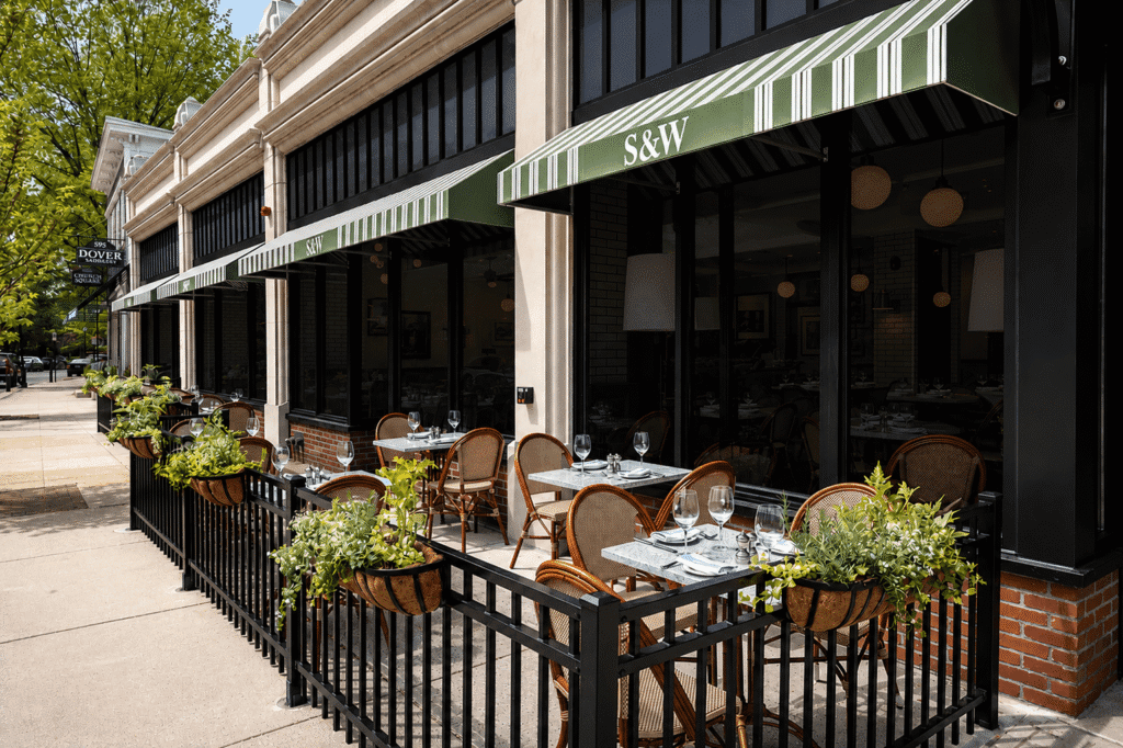 Outdoor seating at a restaurant with green-striped awnings labeled 